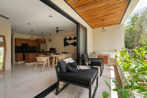 Seamless indoor-outdoor living with an open kitchen, dining area, and private terrace featuring a jacuzzi and lounge seating. Perfect for relaxing and enjoying tropical views.