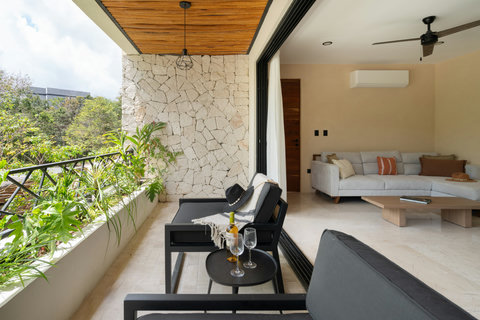Seamless indoor-outdoor living with a stylish lounge terrace, lush greenery, and direct access to a cozy living room. Perfect for relaxing in a serene tropical setting.