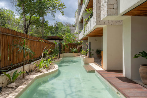 Serene pool surrounded by lush greenery, natural textures, and warm wood details. A peaceful oasis perfect for relaxing and enjoying a tropical atmosphere.