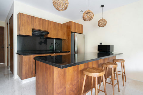 Sleek kitchen with rich wood cabinetry, black stone countertops, and a stylish breakfast bar. Perfect for preparing meals while enjoying a modern and functional space.