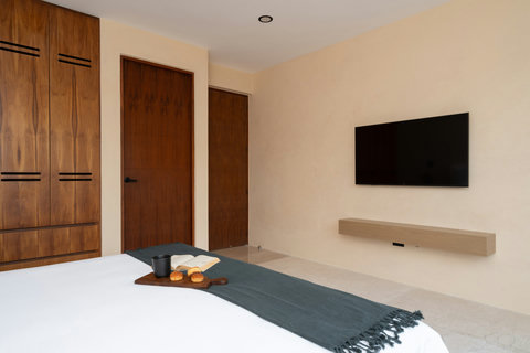 Minimalist bedroom with warm wood finishes, a wall-mounted TV, and a clean, modern design. A calm and functional space perfect for rest and relaxation.