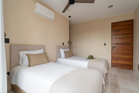 Cozy twin bedroom with soft neutral tones, comfortable beds, and warm wood accents. A calm and inviting space designed for restful and relaxing stays.