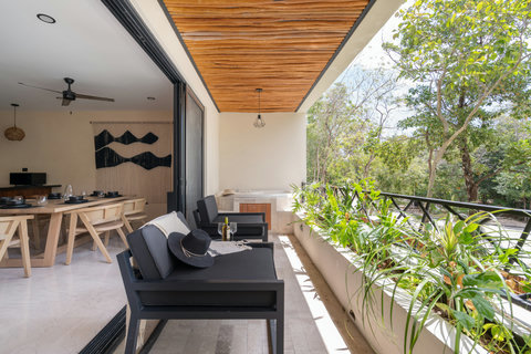 Beautiful terrace with lounge seating and a private jacuzzi, surrounded by lush greenery. Seamlessly connected to the indoor space, perfect for relaxing in a tropical setting.