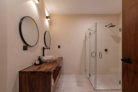 Spacious bathroom with a sleek glass-enclosed shower, double vanity, and warm wood finishes. A refined space combining modern design with natural textures.