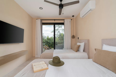 Bright bedroom with two comfortable beds, soft neutral tones, and a private balcony with lush views. A cozy and inviting space perfect for relaxing after a day of exploring.