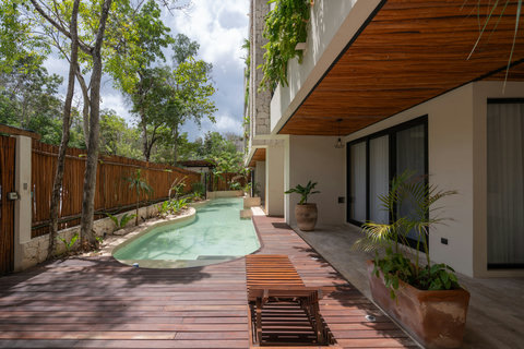 Beautiful pool area with a sleek wooden deck, shaded lounge spaces, and jungle views. Ideal for cooling off or unwinding in a private, nature-filled setting.