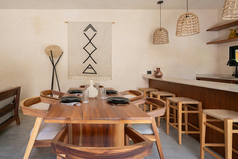 Gather around a beautiful handcrafted dining table beside a modern kitchen with bar seating and warm wood accents. Perfect for shared meals and relaxing moments together.