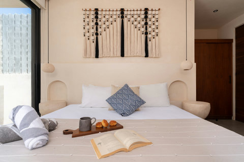 Relax in a cozy boho-inspired bedroom featuring artisan décor, soft neutral tones, and a plush bed designed for restful nights and peaceful mornings in Tulum.