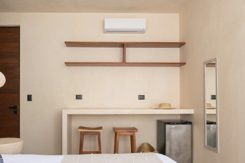 Thoughtfully designed with warm minimalist touches, this cozy bedroom area includes a mini fridge, workspace, and artisan wood accents for added comfort.