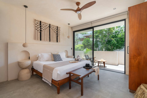Relax in this spacious king suite featuring artisan décor, calming neutral tones, and direct access to a private terrace surrounded by tropical greenery.