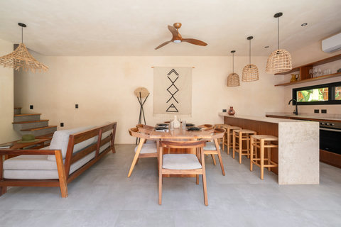 Gather in a stylish open-concept living and dining area featuring warm wood finishes, handcrafted décor, and a fully equipped kitchen designed for comfort and connection.