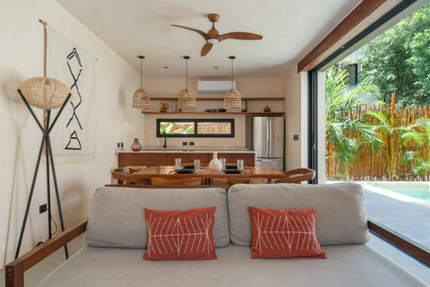 Relax in a beautifully designed open-concept living space featuring warm wood accents, handcrafted décor, and seamless access to the private pool and tropical surroundings.