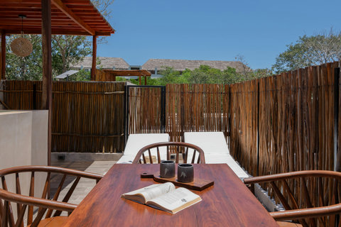 Enjoy peaceful moments on your private terrace with sun loungers, an outdoor dining table, and a relaxing atmosphere surrounded by tropical accents.
