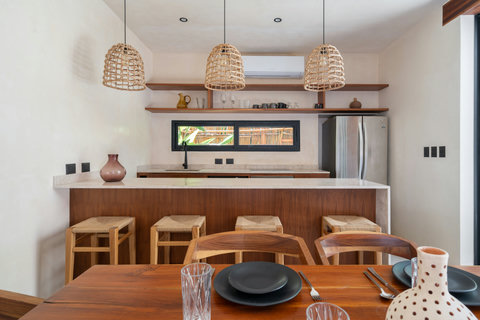 Cook and gather in a stylish fully equipped kitchen featuring warm wood finishes, modern appliances, and elegant bar seating—perfect for meals, coffee, or evening drinks.