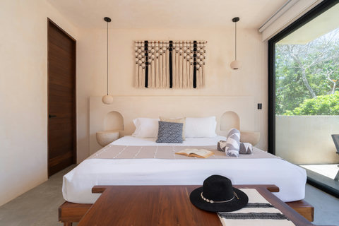 Wake up in a serene king bedroom filled with natural light, handcrafted décor, and direct access to a private terrace surrounded by lush greenery.