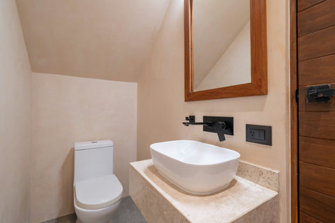 This stylish half bath features clean modern finishes, natural textures, and elegant details designed to complement the home’s warm tropical aesthetic.