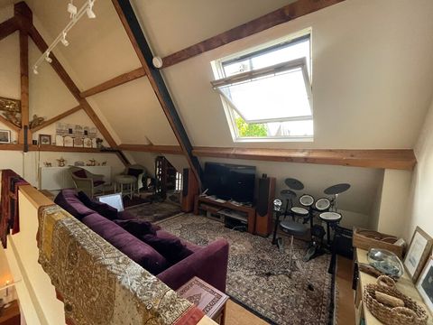 The mezzanine reception room with sofa, TV, electronic drum kit and velux  window. 