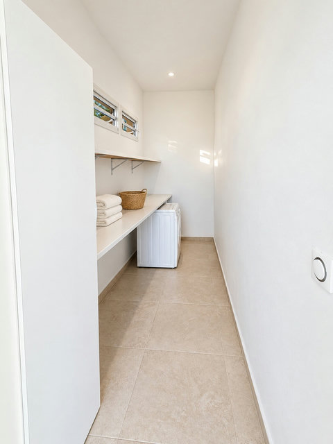 Orison — buanderie avec lave-linge, plan de rangement et étagères pour le linge.