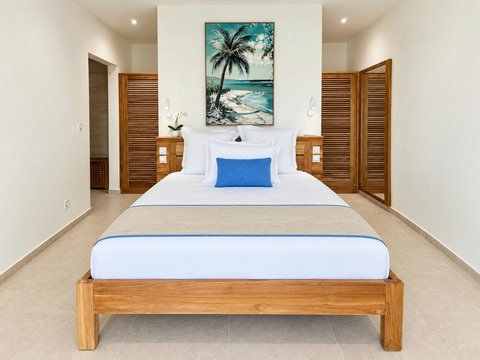 Orison — une des trois suites : lit queen size, chevets et rangements en bois pour un espace nuit indépendant.
