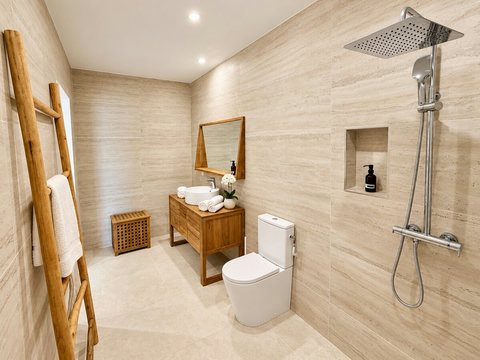 Loona — salle d’eau avec douche à pommeau de tête, vasque sur meuble en bois et toilettes.