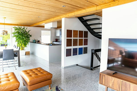 The entire main level is designed for effortless socializing, seamlessly integrating the gourmet kitchen, dining area, and living space. Features the modern spiral staircase and local artwork. The perfect social hub for Swiss Dream Living!