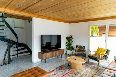Enjoy movies and shows on the large 65-inch Smart TV with high-speed Wi-Fi. The unique spiral staircase and cozy seating complete this modern, comfortable living space by Swiss Dream Living.