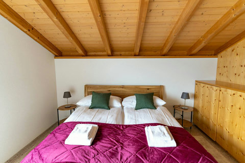 King bed for two (Bedroom-3) Enjoy the full view of the exposed wood-beamed ceiling and beautiful custom wood furnishings. Features comfortable bedding and integrated storage for a clutter-free, peaceful stay. Your premium Swiss Dream Living retreat.