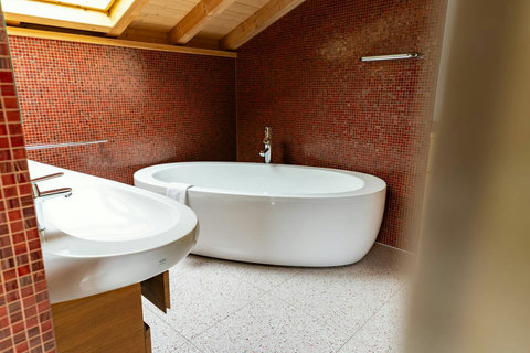 Spa-Quality Soaking Tub.  Indulge in a tranquil soak in this luxury freestanding tub, perfectly positioned beneath a skylight. Featuring premium fittings and unique mosaic tiling—a relaxing, designer touch from Swiss Dream Living.