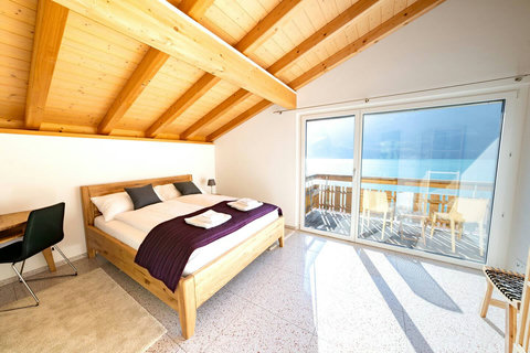 Sunlit Top-Floor Suite. Vaulted wood ceilings and large windows maximize light. Direct balcony access offers stunning views for your morning coffee.