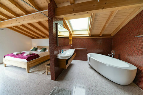 Luxury Attic Suite: Soak under the skylight in your freestanding tub! Features exposed wood beams, premium fittings, and a comfortable bed, all in one unique space. Experience the signature Swiss Dream Living style in the Swiss Alps loft.