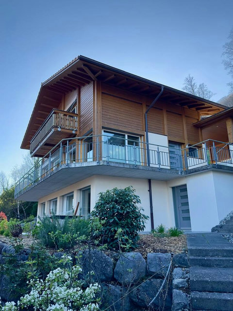 Authentic Swiss Design. Beautiful blend of traditional wood chalet and modern lower-level finish. This view captures the dual-level design, secure entrance, and charming garden landscaping. Welcome home to Chalet Swiss Dream by Swiss Dream Living.