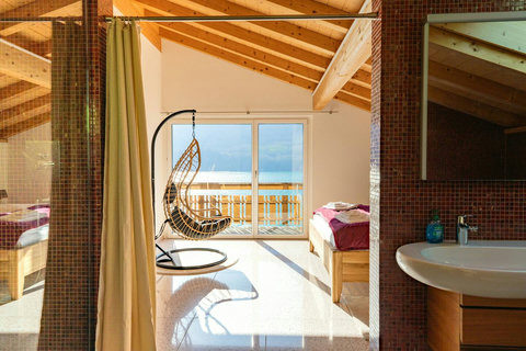 Sun-Drenched Attic Suite. ☀️ Wake up to the stunning Lake Brienz View framed by the room's unique architectural elements. Features a private washroom access and a cozy hanging chair