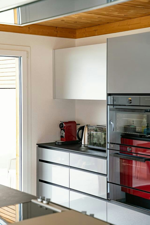 Modern Convenience. Features high-end integrated appliances, including a built-in oven, and a dedicated Nespresso coffee station. Sleek, high-gloss cabinetry ensures both style and functionality in this Swiss Dream Living gourmet kitchen.