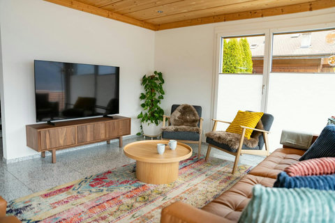 Natural Luxury Design. This cozy living area is furnished with premium natural materials: rich leather seating, solid wood furniture, and soft, natural rugs. A perfect blend of comfort and style that defines the Swiss Dream Living experience.