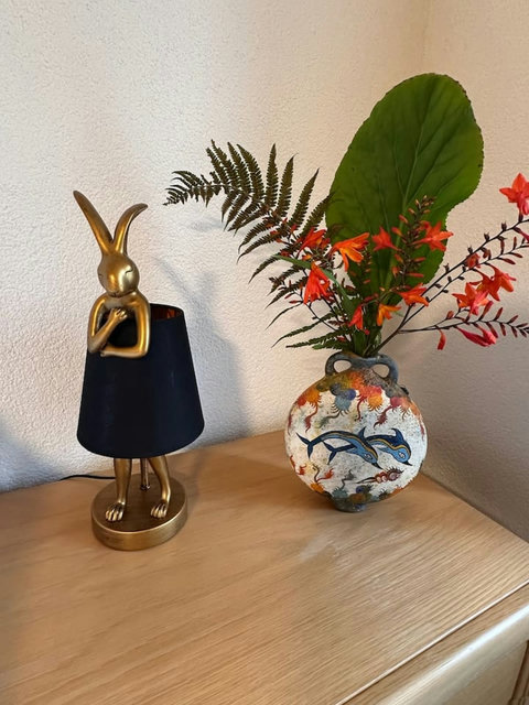 Elegant décor featuring a stylish lamp paired with a decorative flower pot, adding charm and warmth to the space