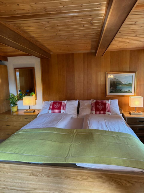 Comfortable double bed with clean linens and bedside lamps in a warm bedroom.
