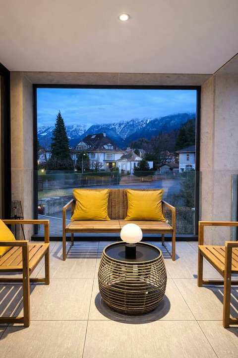 A private balcony with cushioned outdoor seating and open views toward the mountains and surrounding neighborhood.