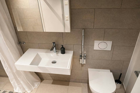 Modern bathroom with a full-size bathtub, neutral stone tiles, and a clean, minimalist design.