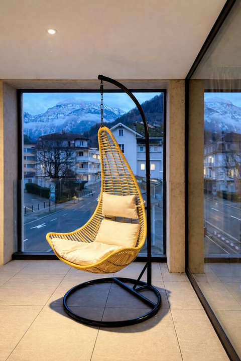 A cozy balcony corner with a comfortable lounge chair and soft cushions, overlooking the quiet streets of Interlaken.