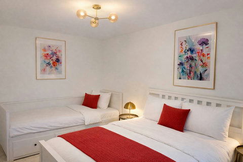 A bright and comfortable bedroom with 1 double and 1 single bed, fresh white linens, and warm bedside lighting.