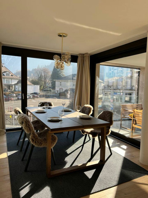 Enjoy meals with sunlight and mountain charm in a cozy dining space overlooking a peaceful Swiss village.