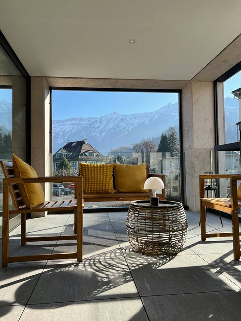 Relax on your private balcony with panoramic Swiss Alps views and cozy seating for peaceful mornings.