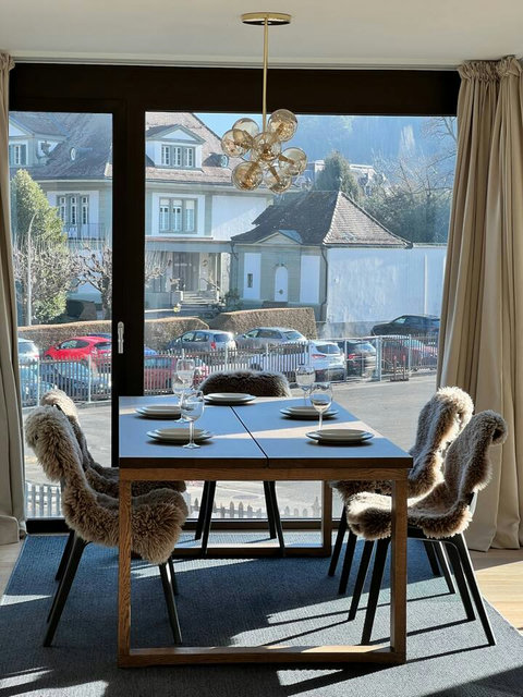 Dine with a view in a cozy alpine setting, with large windows and natural light overlooking the Swiss village.