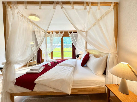 Manor 2 canopy bedroom — elegant draped comfort with soft alpine light, created for restful luxury after a day in the Swiss mountains.