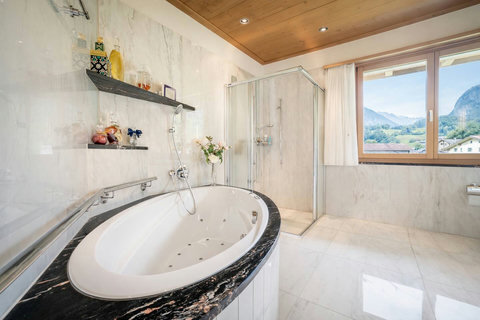 Spa-style Chalet Manor bathroom — marble finishes, whirlpool bath, walk-in shower and mountain views for a lavish alpine escape.
