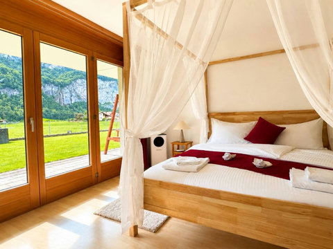 Manor 2 Bedroom 1 at Chalet Swiss Dream Manor — canopy bed, garden access and mountain views for a peaceful Swiss Alps escape.