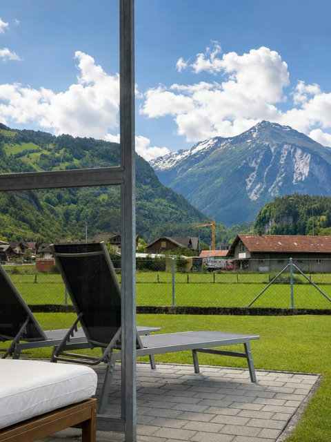 Manor 2 sunbed view — relax beneath dramatic Swiss Alps scenery, with open green fields and peaceful mountain views from Chalet Manor.