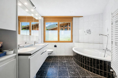 Manor 2 bathroom at Chalet Swiss Dream Manor — spacious, bright and elegant with a bathtub, double vanity and mountain views for a relaxing alpine stay.