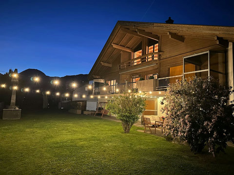 Private garden at night — glowing lights, peaceful lawn and easy ground-floor access for relaxed Swiss Alps evenings.