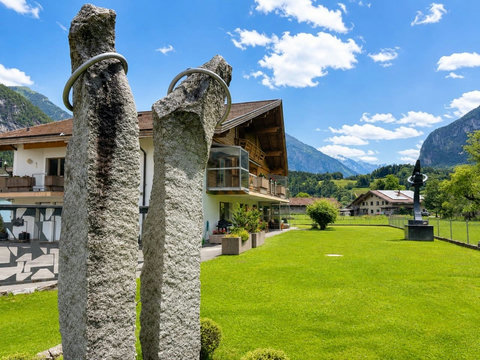 Manor 2 garden view — outdoor stone sculpture, wide lawn and Swiss Alps scenery for a peaceful alpine escape.